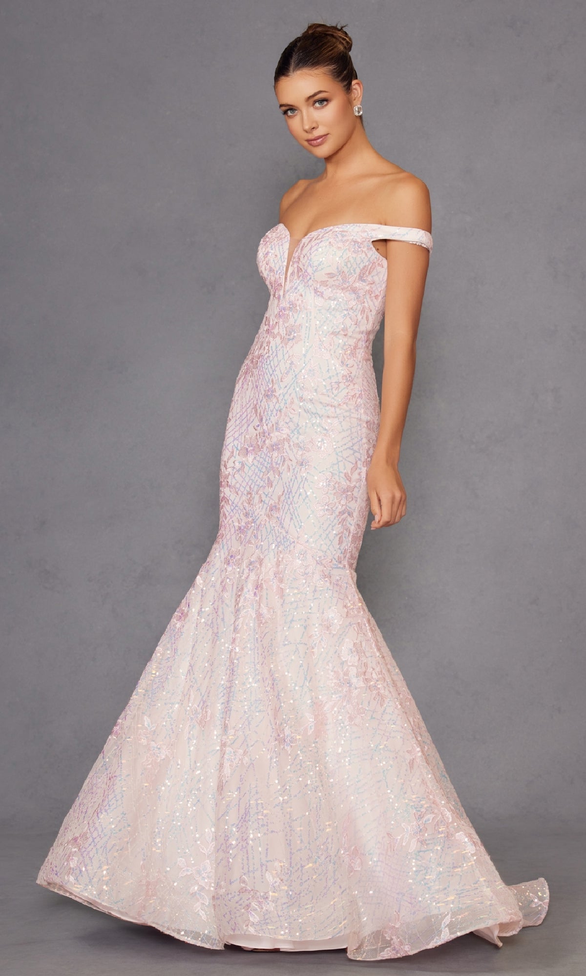A woman in the Off-the-Shoulder Sequin Mermaid Prom Dress 2412, a blush pink gown with a fitted bodice and flared skirt, poses against a plain gray background.